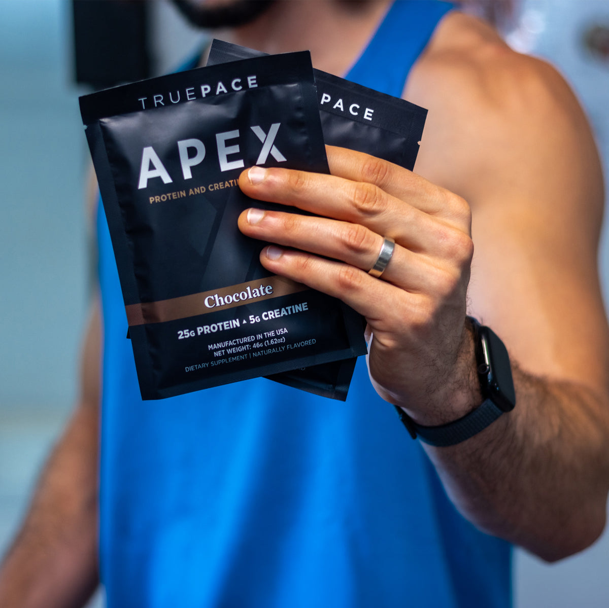 A man holds truePACE APEX Chocolate single-serve protein and creatine packets